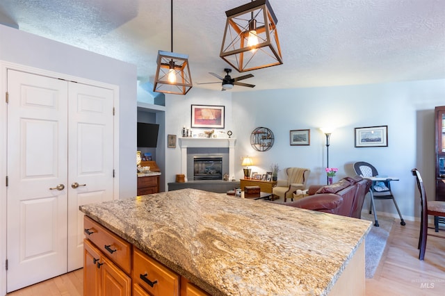 4023 N Bayou Ln, Boise, ID 83703 - kitchen featuring open floor plan, ceiling fan, a tile fireplace, light wood-type flooring, and a center island