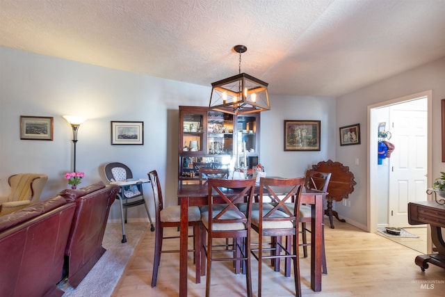 4023 N Bayou Ln, Boise, ID 83703 - dining area with light wood-type flooring, a chandelier, baseboards, and a textured ceiling
