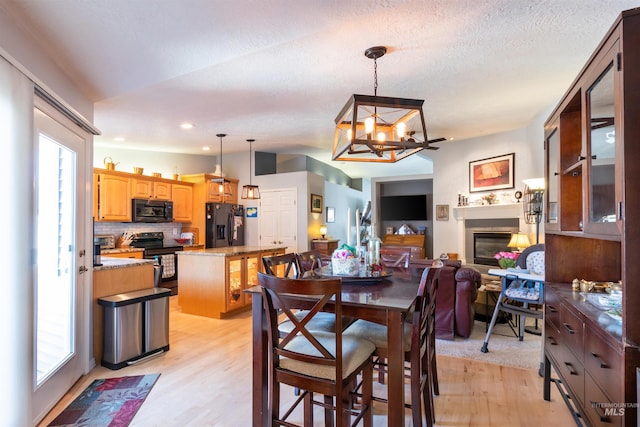 4023 N Bayou Ln, Boise, ID 83703 - dining area with light wood finished floors, a chandelier, a glass covered fireplace, recessed lighting, and a textured ceiling