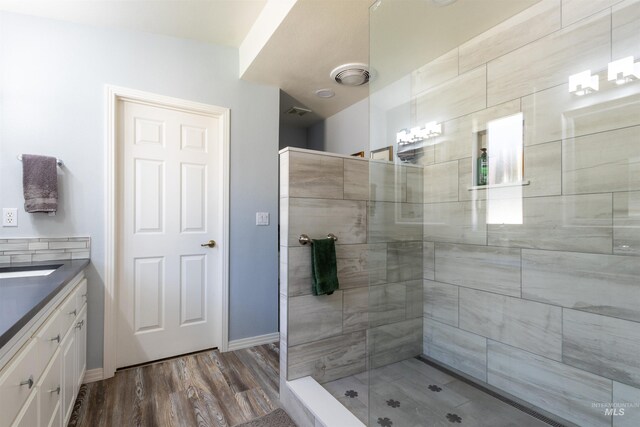 4023 N Bayou Ln, Boise, ID 83703 - bathroom featuring a tile shower, wood finished floors, vanity, and baseboards