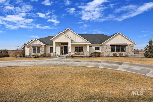 craftsman house featuring board and batten siding, a porch, concrete driveway, a front yard, and stone siding