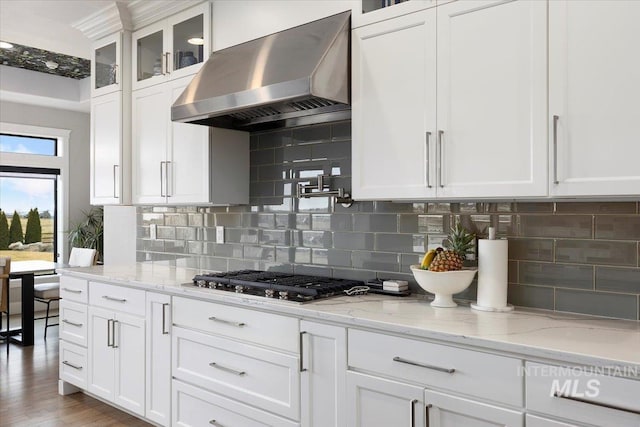 kitchen with white cabinets, ventilation hood, glass insert cabinets, and stainless steel gas stovetop