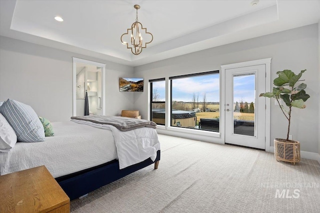 carpeted bedroom with access to outside, a tray ceiling, ensuite bath, an inviting chandelier, and baseboards