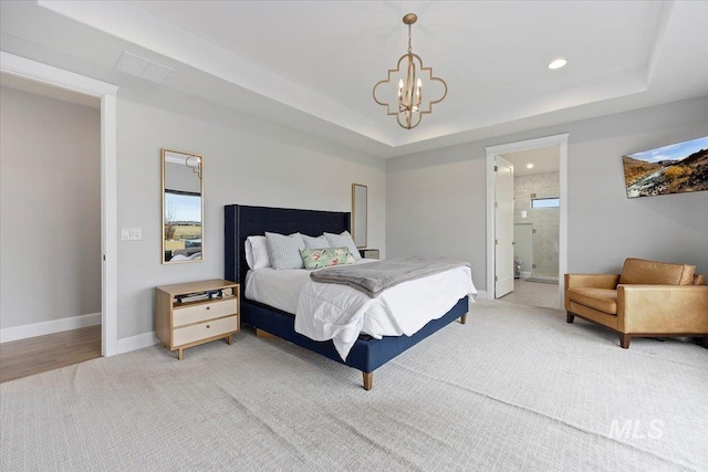 bedroom with a tray ceiling, baseboards, a notable chandelier, and connected bathroom