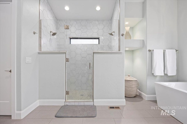 full bath with tile patterned flooring, a soaking tub, a shower stall, and baseboards