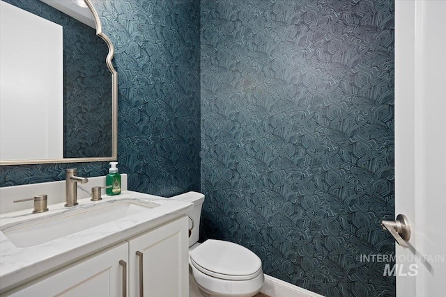 bathroom with wallpapered walls, toilet, and vanity