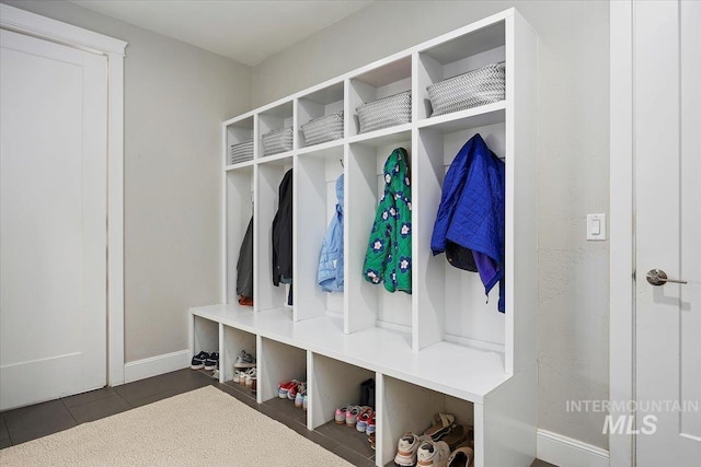 mudroom with baseboards and dark tile patterned flooring