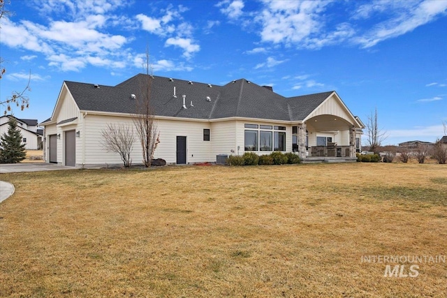 rear view of house with board and batten siding, concrete driveway, a lawn, and a garage