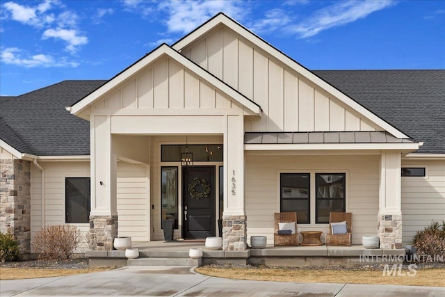 view of front of house with stone siding, board and batten siding, a porch, and roof with shingles