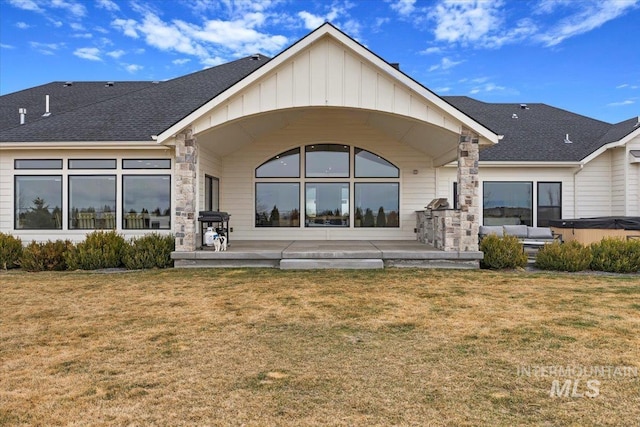 back of house featuring a yard, a patio area, and board and batten siding