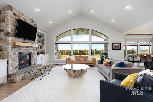 living area featuring high vaulted ceiling, built in features, wood finished floors, recessed lighting, and a stone fireplace