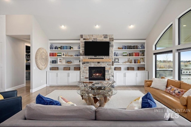 living room with vaulted ceiling, a fireplace, light wood-type flooring, and baseboards