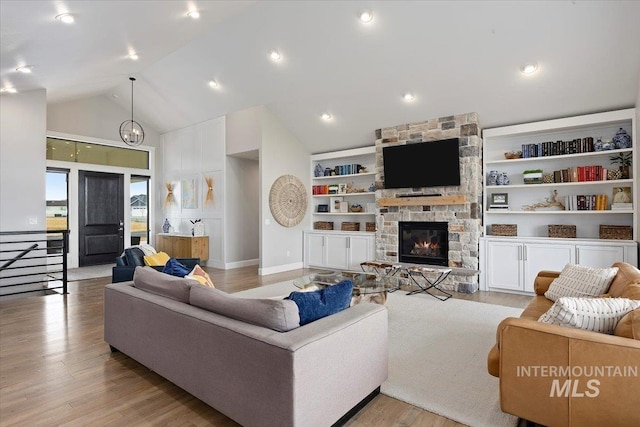 living area featuring light wood finished floors, baseboards, built in features, a fireplace, and high vaulted ceiling