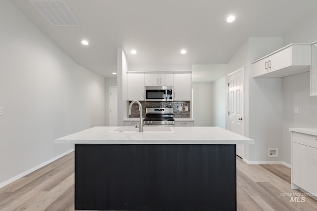 kitchen featuring white cabinets, light wood-type flooring, sink, and appliances with stainless steel finishes