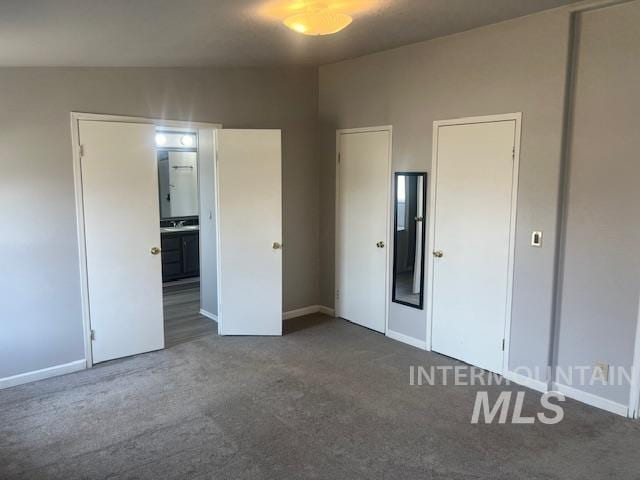 unfurnished bedroom with ensuite bath, baseboards, and carpet floors