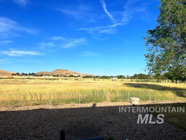 view of yard featuring a rural view, a mountain view, and fence