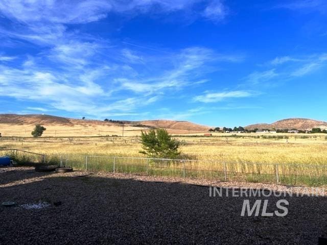 view of yard featuring a rural view, fence, and a mountain view