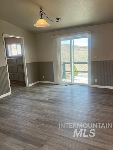 spare room featuring a wainscoted wall, a textured ceiling, and wood finished floors