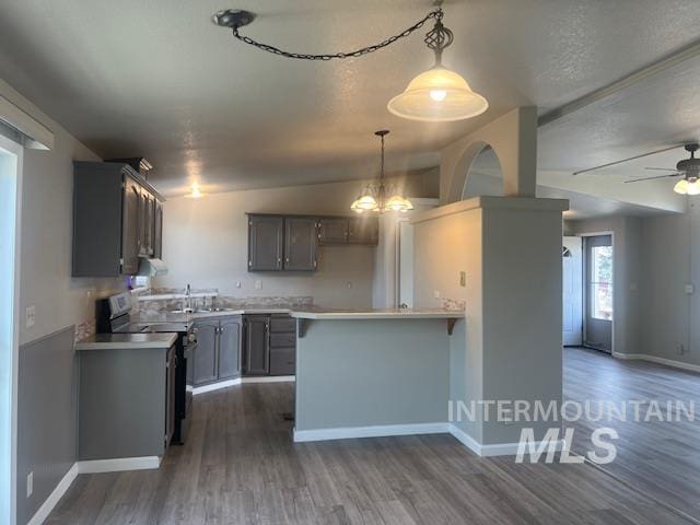 kitchen with a peninsula, light countertops, electric stove, and dark wood-type flooring