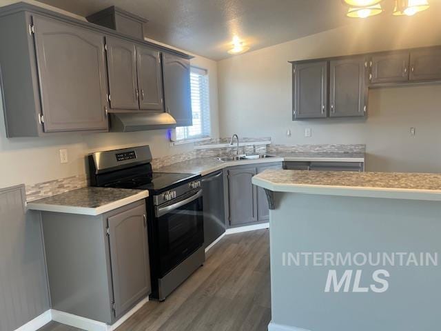 kitchen featuring under cabinet range hood, gray cabinets, appliances with stainless steel finishes, wood finished floors, and a sink