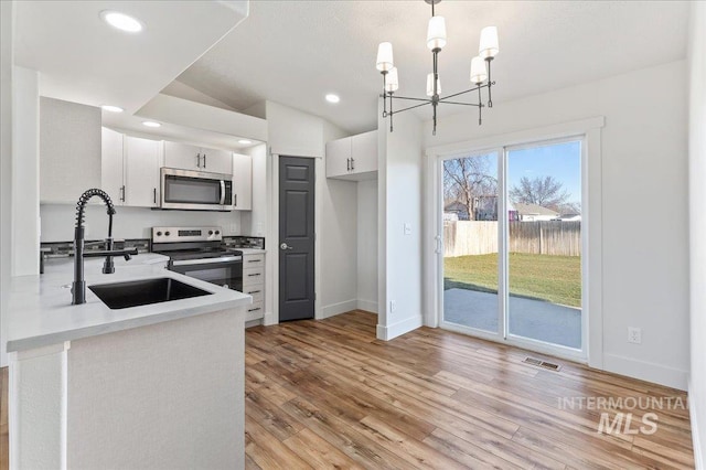 kitchen with sink, stainless steel appliances, pendant lighting, and white cabinetry