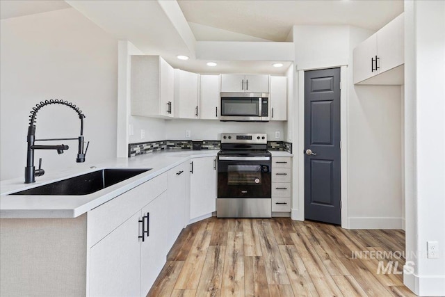 kitchen with sink, white cabinetry, light wood-type flooring, and appliances with stainless steel finishes