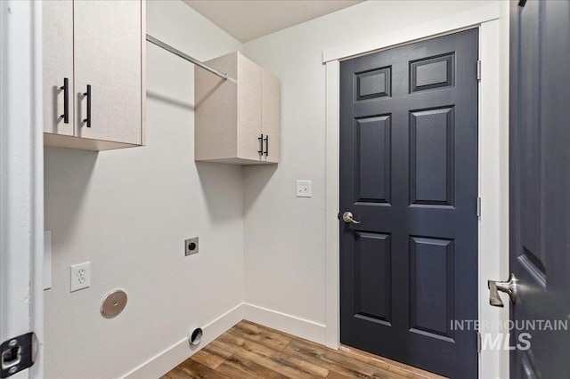 washroom featuring electric dryer hookup, cabinets, and light hardwood / wood-style flooring