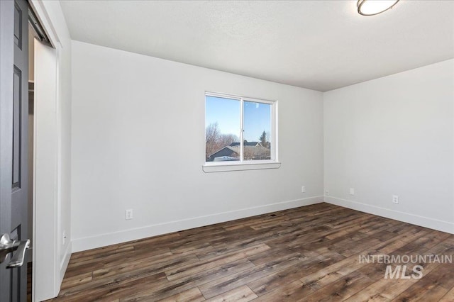 empty room with dark hardwood / wood-style flooring