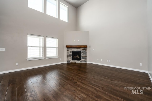 unfurnished living room with a fireplace, a high ceiling, and dark hardwood / wood-style floors