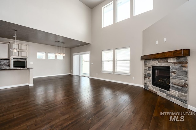 unfurnished living room featuring a fireplace, dark wood-type flooring, and plenty of natural light