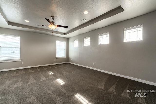 carpeted spare room featuring a tray ceiling, a textured ceiling, and ceiling fan