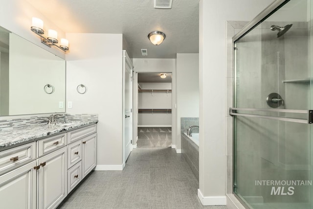 bathroom with vanity, independent shower and bath, and a textured ceiling