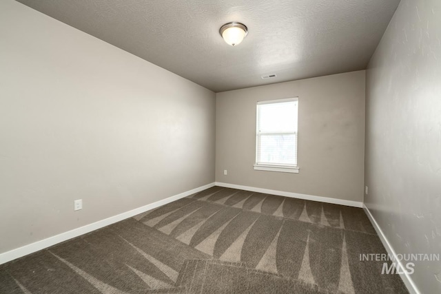 carpeted spare room featuring a textured ceiling