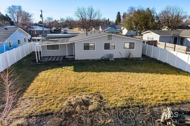 rear view of property with central AC unit and a lawn