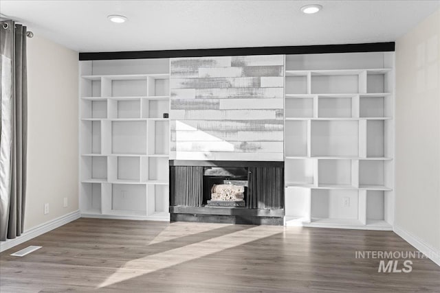 room details featuring hardwood / wood-style flooring, built in shelves, and a multi sided fireplace