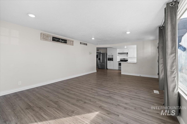 unfurnished living room featuring dark wood-type flooring and a textured ceiling