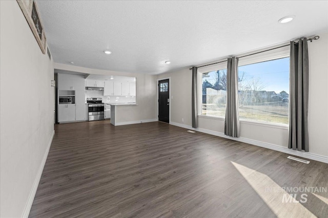 unfurnished living room with dark hardwood / wood-style floors and a textured ceiling