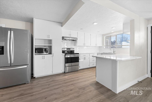 kitchen featuring stainless steel appliances, kitchen peninsula, sink, and white cabinets