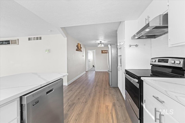 kitchen with backsplash, stainless steel appliances, light stone countertops, and white cabinets