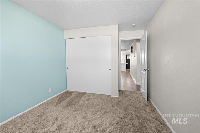 unfurnished bedroom featuring a closet, carpet flooring, and a textured ceiling