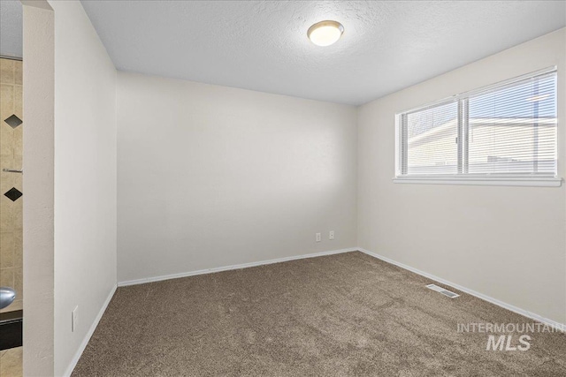 carpeted spare room with a textured ceiling