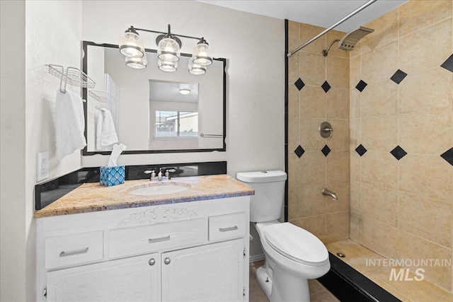 bathroom with tiled shower, vanity, and toilet