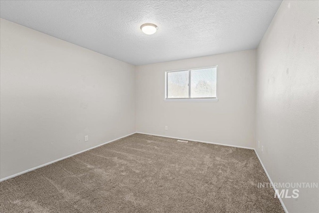 unfurnished room featuring carpet flooring and a textured ceiling