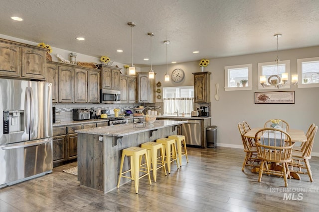 kitchen with a breakfast bar area, an inviting chandelier, stainless steel appliances, backsplash, and a center island