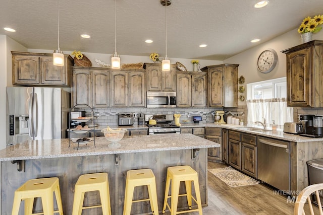 kitchen featuring stainless steel appliances, a kitchen bar, light wood-type flooring, backsplash, and a center island