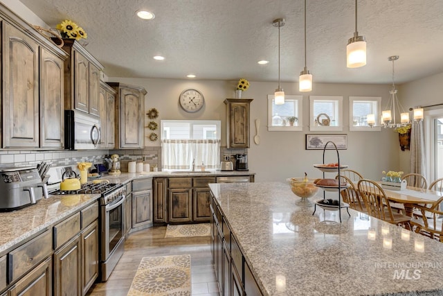 kitchen with plenty of natural light, backsplash, appliances with stainless steel finishes, and a sink