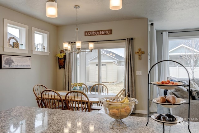 dining area featuring baseboards, a textured ceiling, and an inviting chandelier