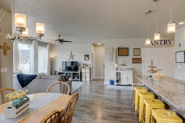 dining room with dark wood finished floors, baseboards, a textured ceiling, and ceiling fan