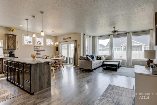 kitchen with wood finished floors, a ceiling fan, pendant lighting, a kitchen breakfast bar, and a center island