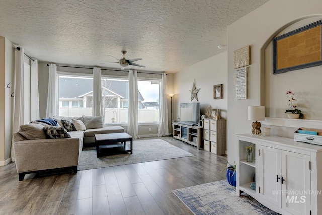 living room with wood finished floors, a textured ceiling, and ceiling fan